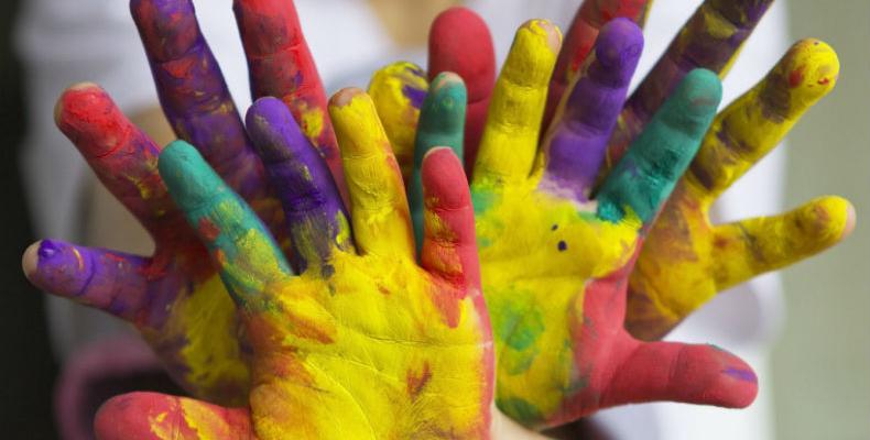 Children's hands covered in brightly coloured paint