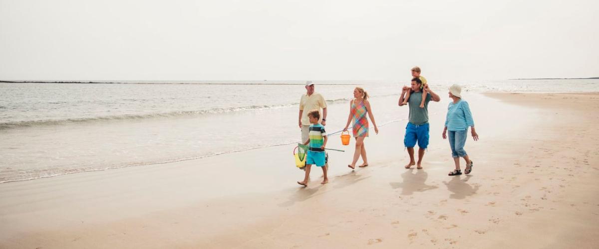 An family with children and grandparents walking on empty beach