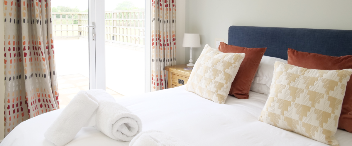 King bed with blue headboard and showing patio doors to garden