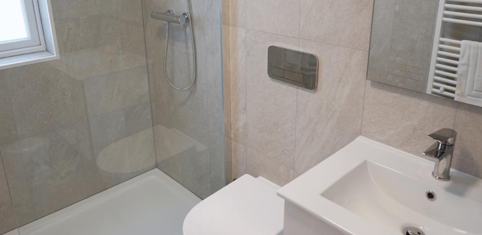 Smart light-grey tiled bathroom with large shower and glass screen