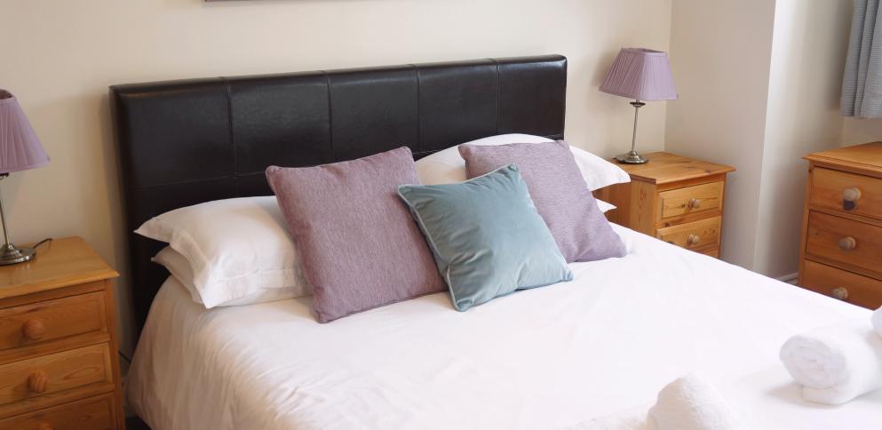 bed with leather bedstead and purple cushions
