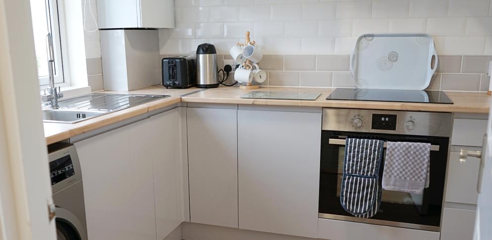 light grey gloss kitchen with wooden counters an in-built oven