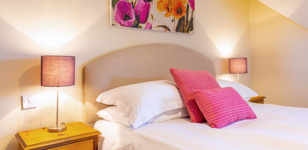 bed with hot pink cushions and bright picture