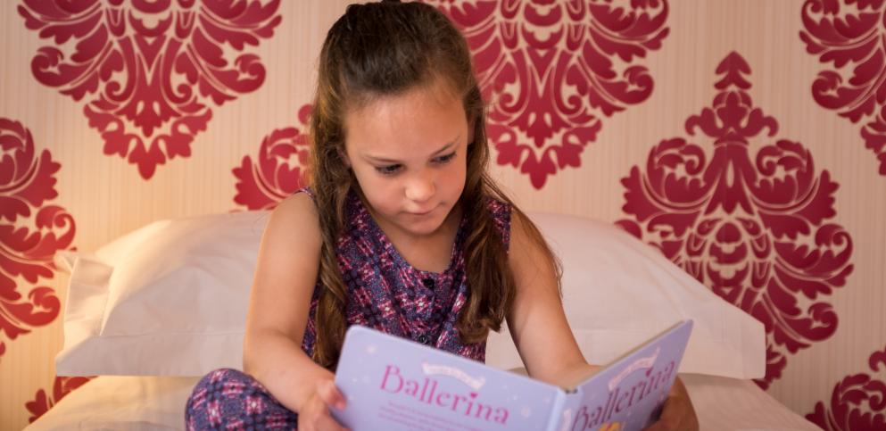 girl reading a book in a pink bedroom