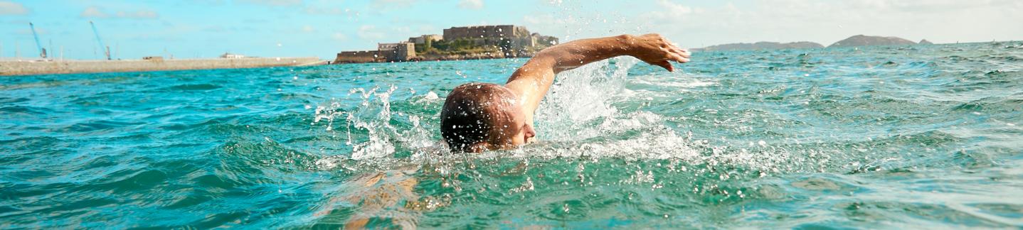 man swimming in sea in Havelet Bay in Guernsey