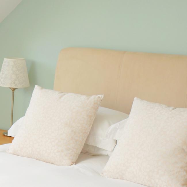 bed with cream headboard and white linen